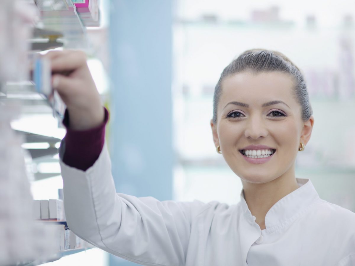 Happy cheerful pharmacist chemist woman standing in pharmacy drugstore